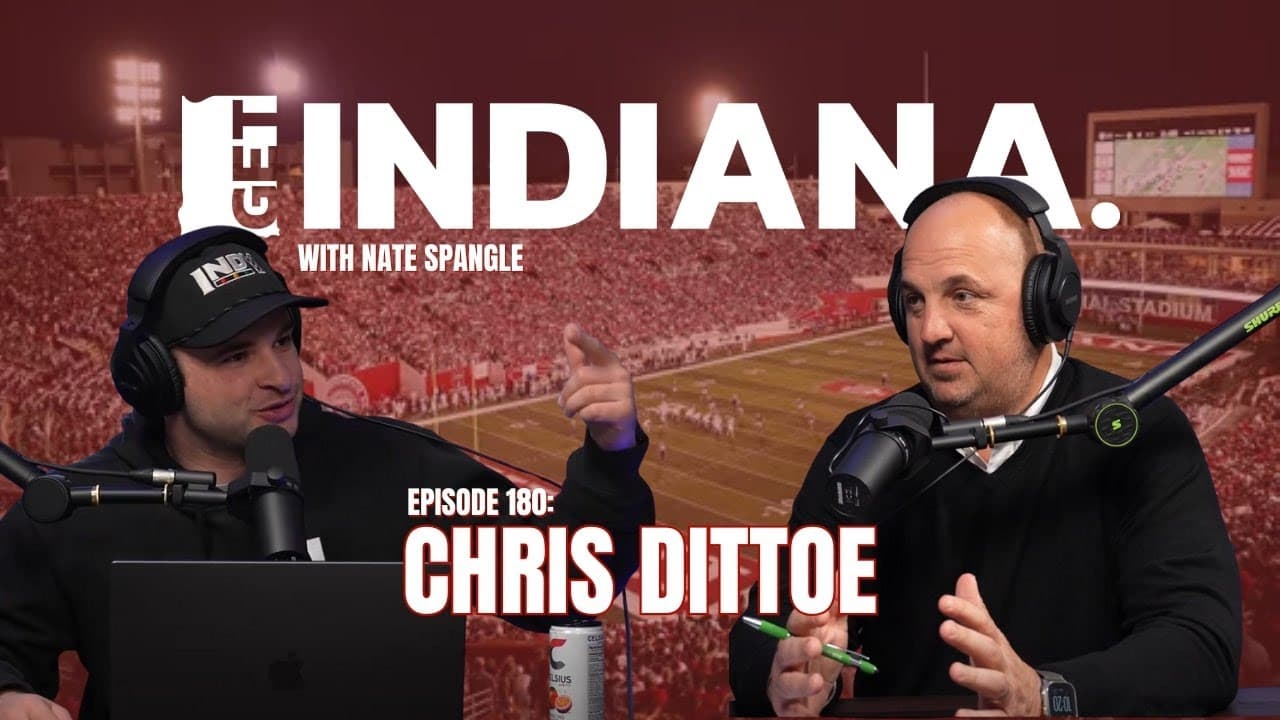 Two men in a podcast studio discuss business against a backdrop of a football stadium in Indiana.