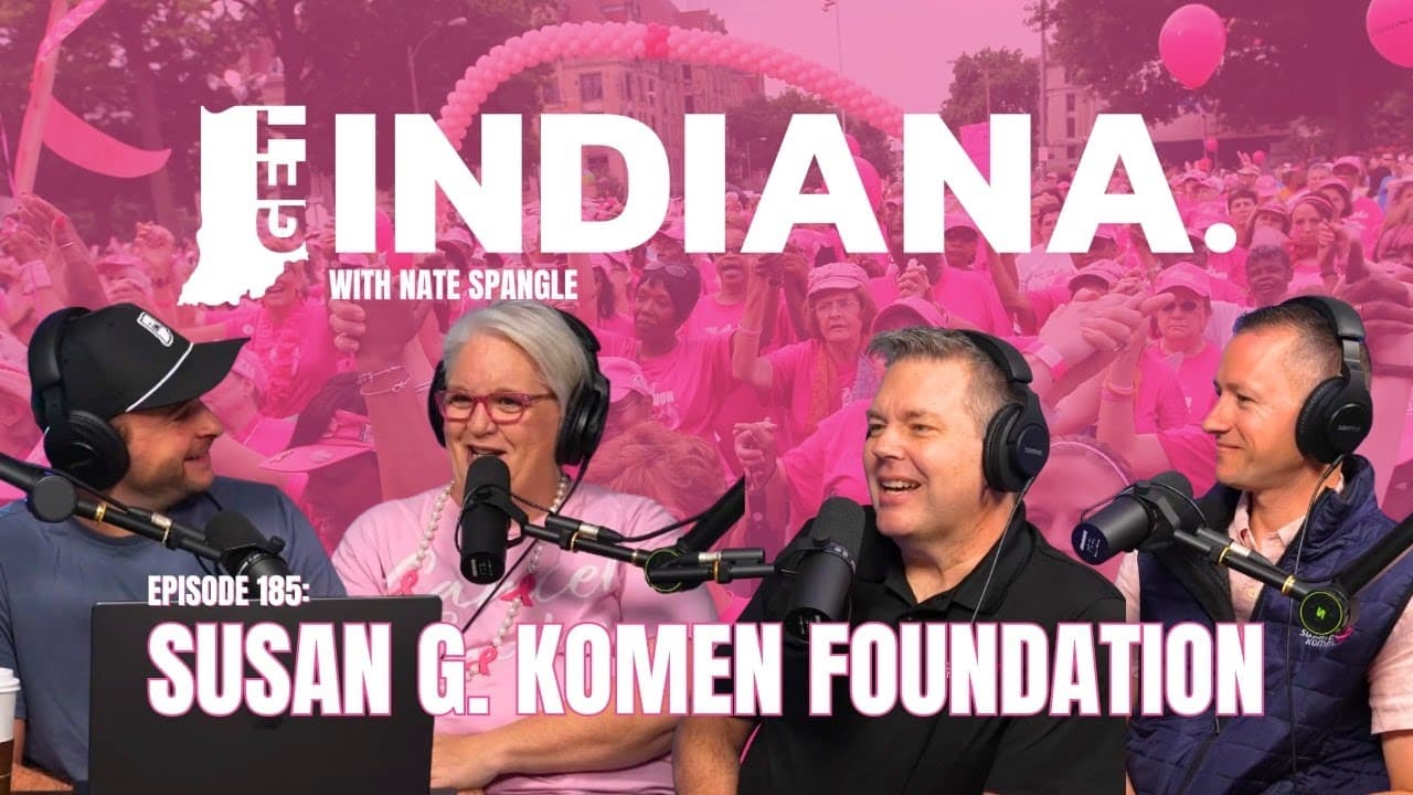 Podcast hosts discuss the Susan G. Komen Foundation against a vibrant pink backdrop, symbolizing breast cancer awareness.