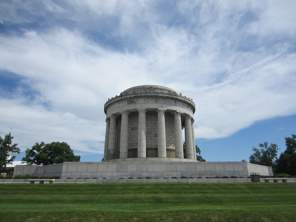 The George Rogers Clark Memorial in Indiana. A classical style building with pillars sits on a grassy area under a cloudy sky.