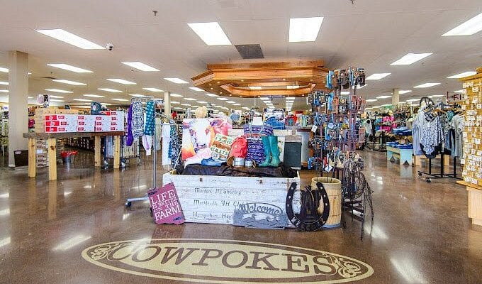 Inside Cowpokes store with clothing and accessories on display. A wooden sign says "Lift the Farm."