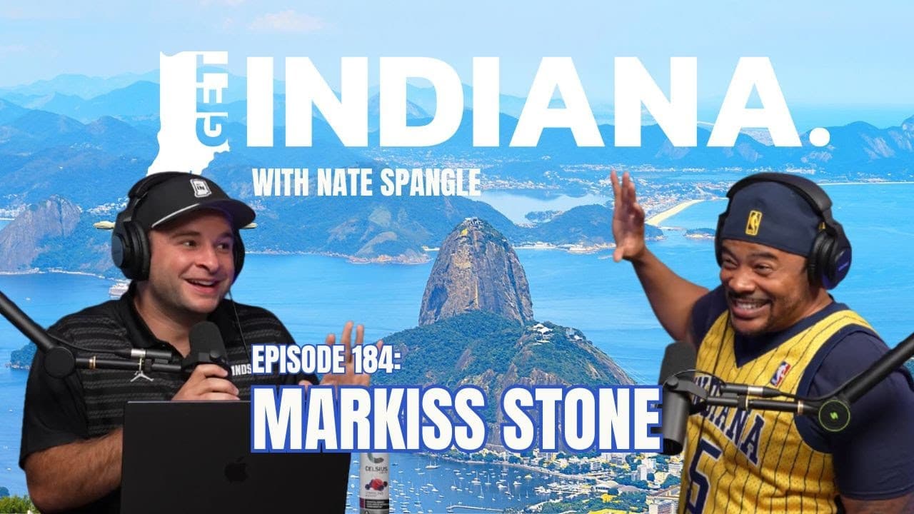 Two men in casual attire discuss food and culture against a scenic backdrop, promoting Indiana's culinary scene.